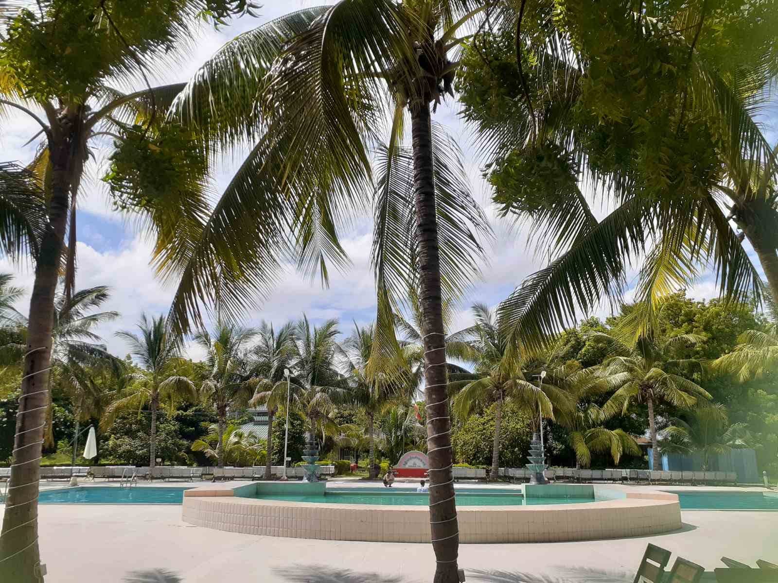 The outdoor pool and fountain framed by coconut palms at the Meiktila Hotel